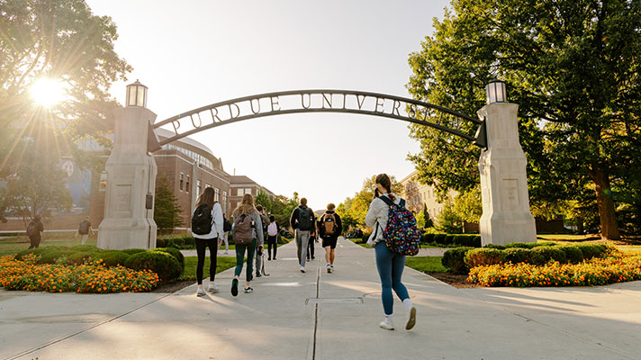 Students walk under the Purdue University arch on campus