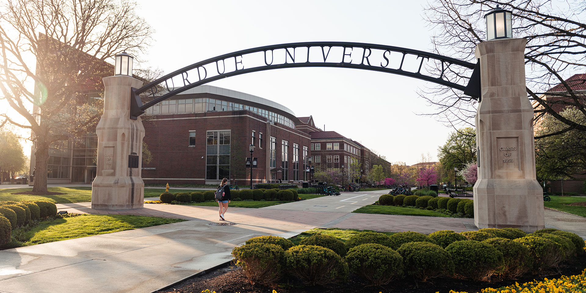 A student walks under the Purdue University entrance