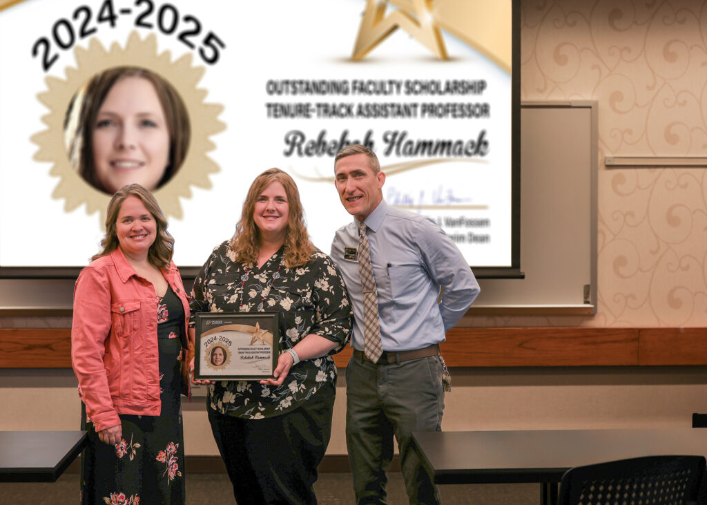 Dr. Rebekah Hammack holding a certificate. Standing with her are Jennifer Smith and Phillip VanFossen.