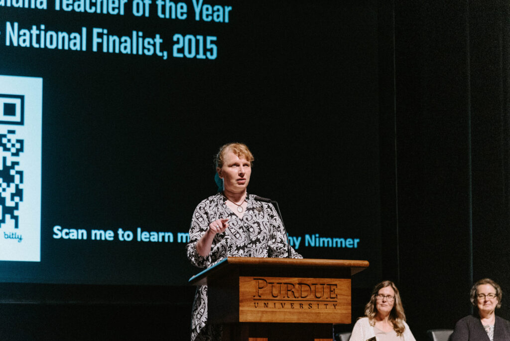 Kathy Nimmer speaking at a podium on the Loeb Playhouse stage.