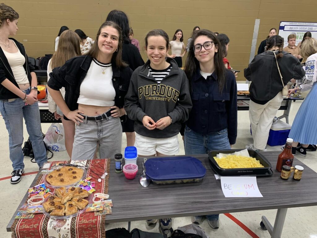 Three BFTF fellows standing behind a table full of Belgian food.