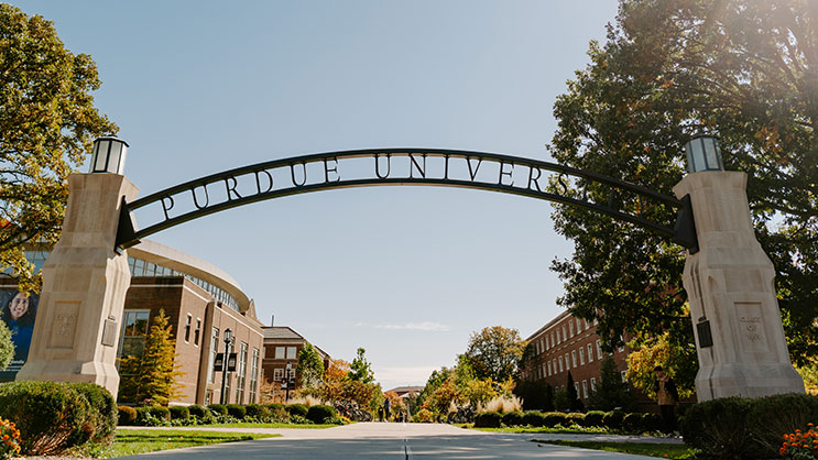 The Purdue University arch overlooking Stadium Mall in front of a clear blue sky.