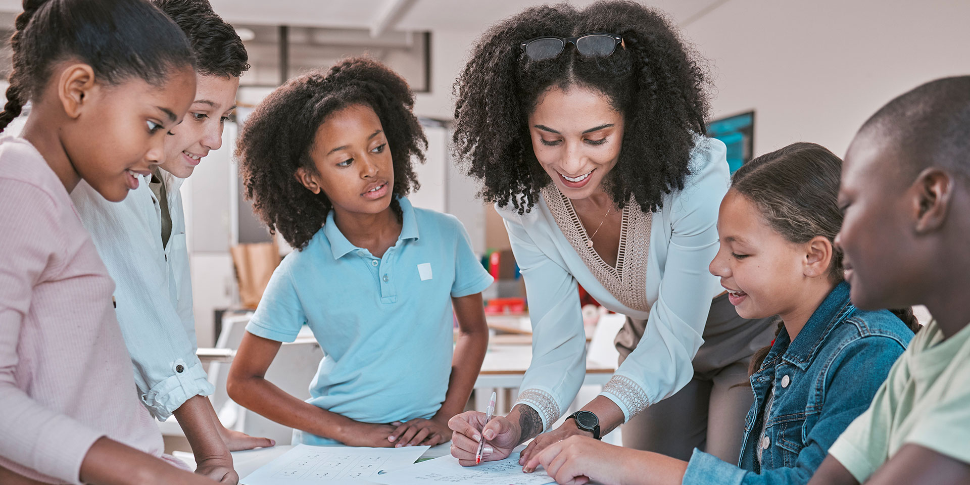 A teacher points out something in a book to a group of students
