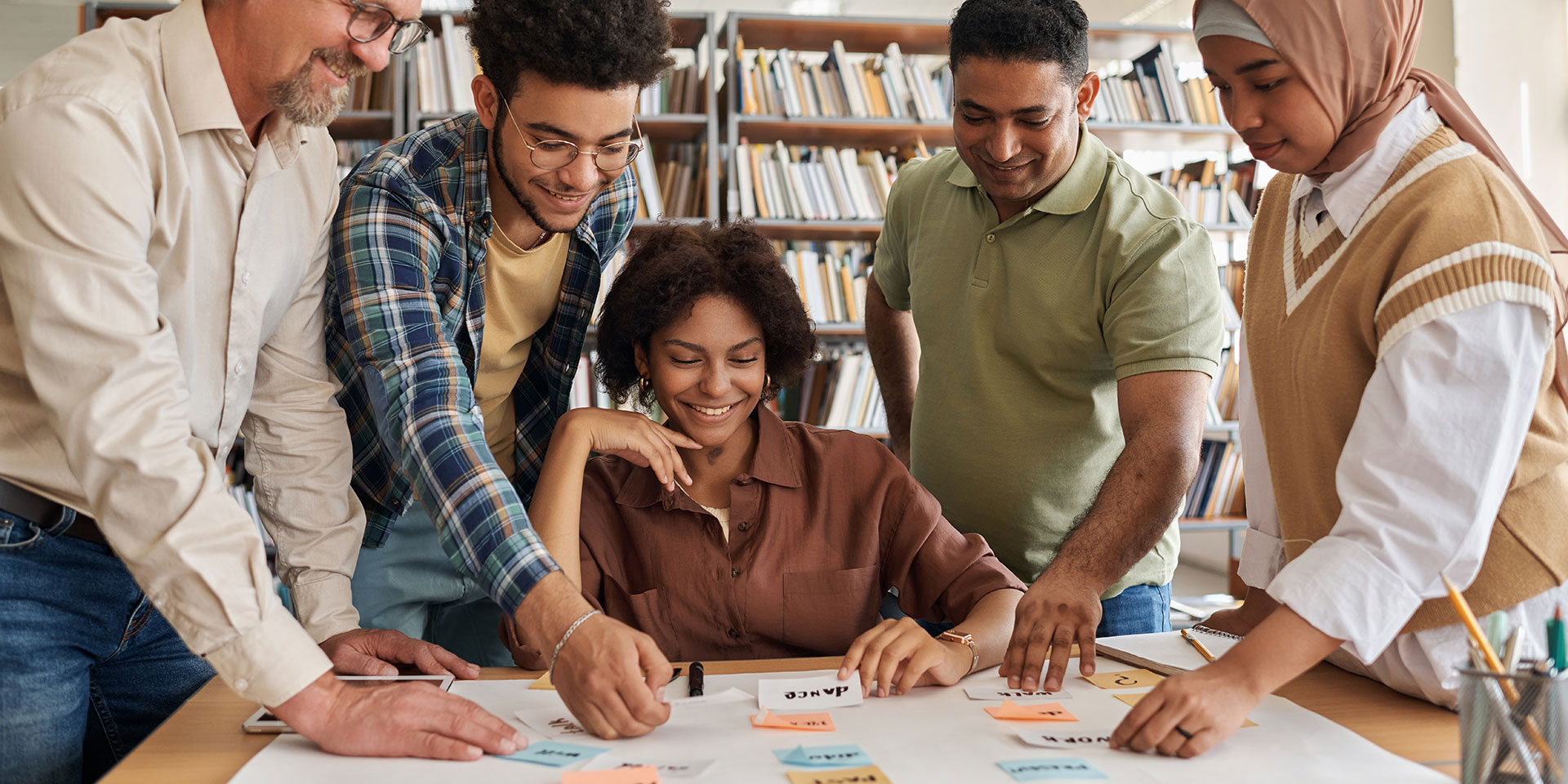 Students and a teacher work on a project with sticky notes on a table