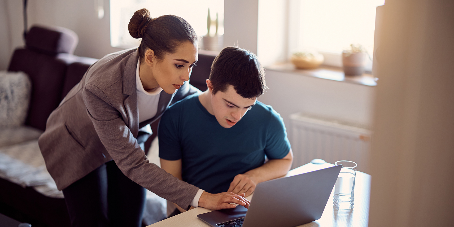 A teacher works with a special education student using a laptop.