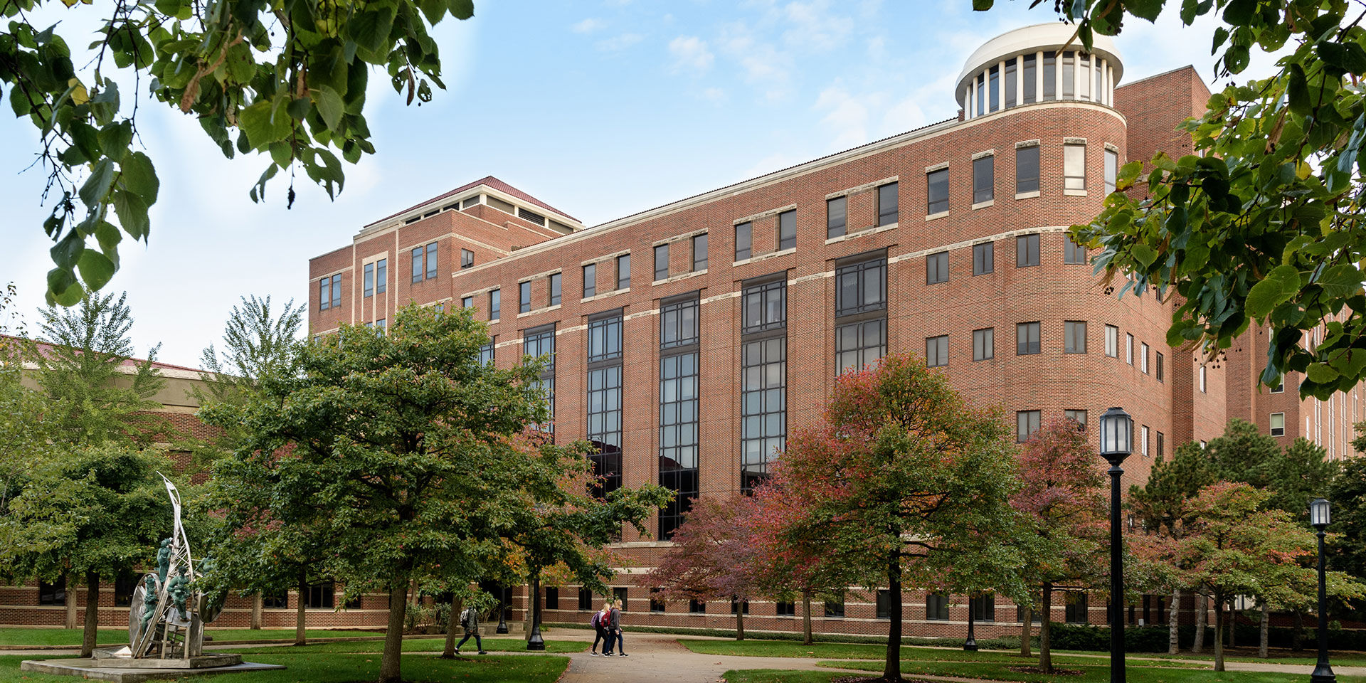 A scenic view of Beering Hall. In the foreground, green trees slightly obscure the building.
