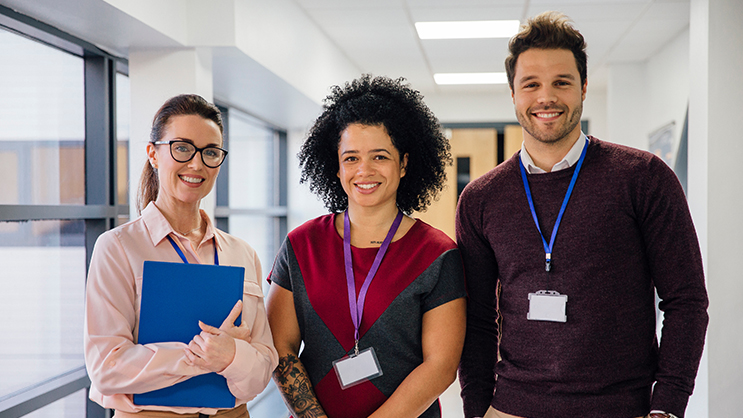 Three teachers standing next to each other in a hallway.