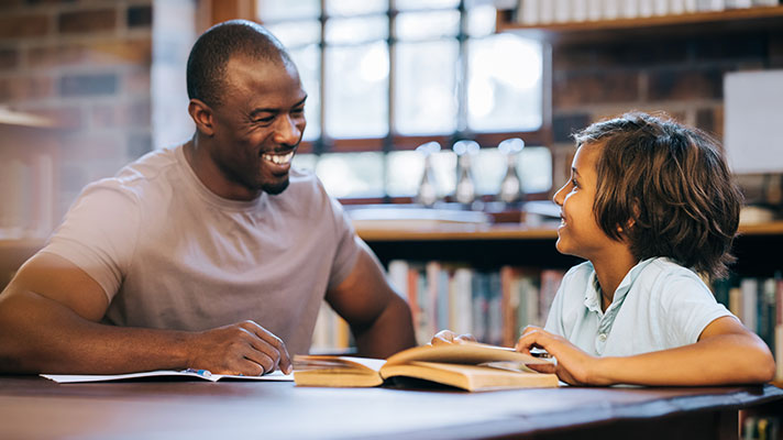 A male teacher works with a student in a library
