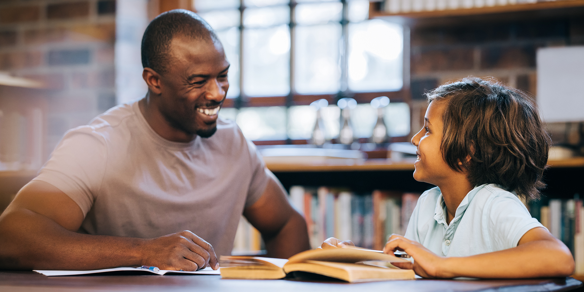 A male teacher works with a student in a library.