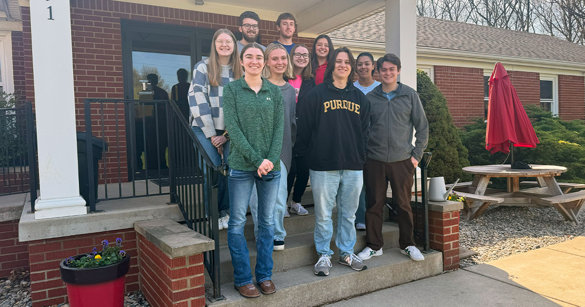 A group of elementary education students standing on the front steps outside of the Montessori School of Greater Lafayette.