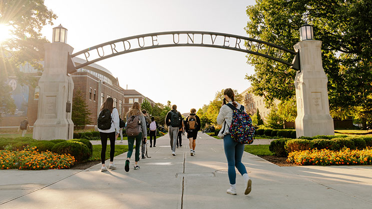 A group of students walking underneath the Purdue Arch.