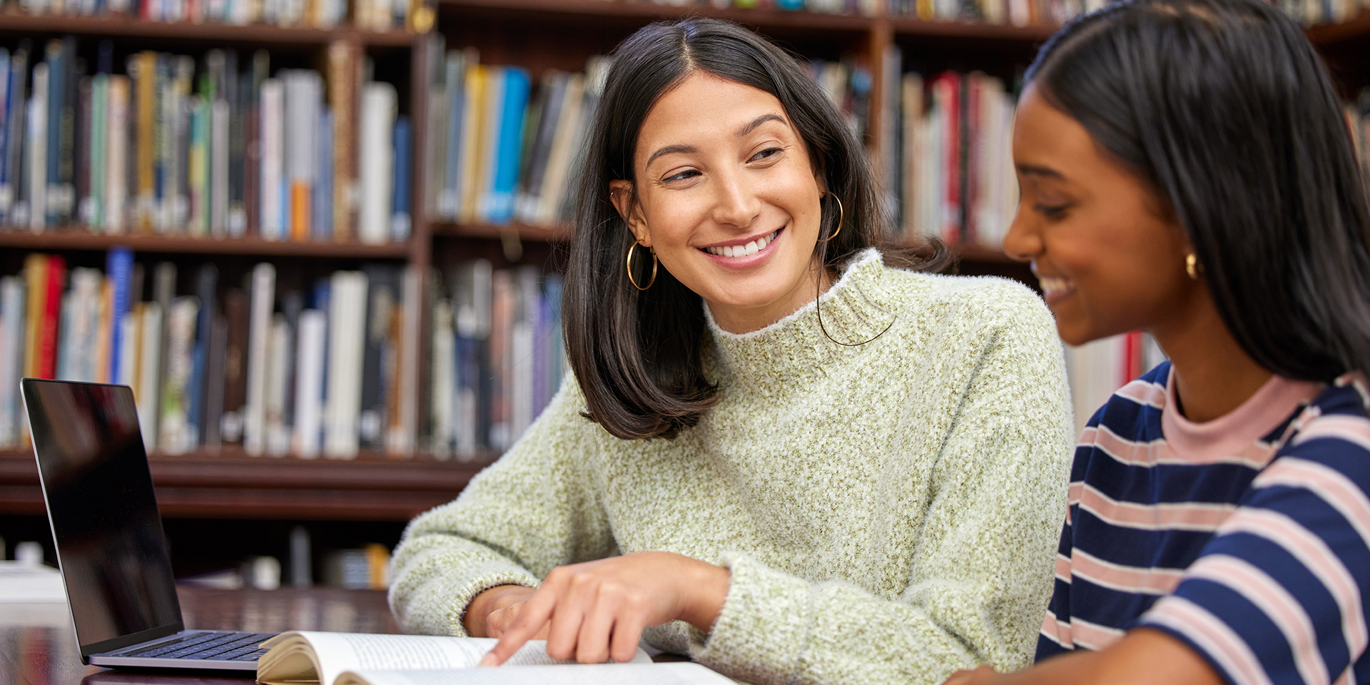 A college advisor works with a student in the library.