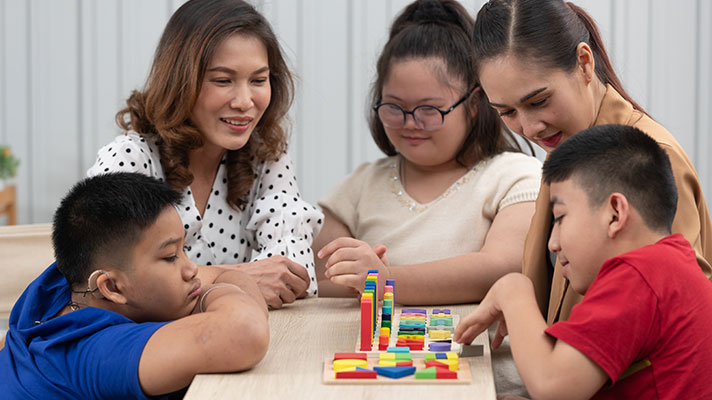 Two teachers work with three students with special needs