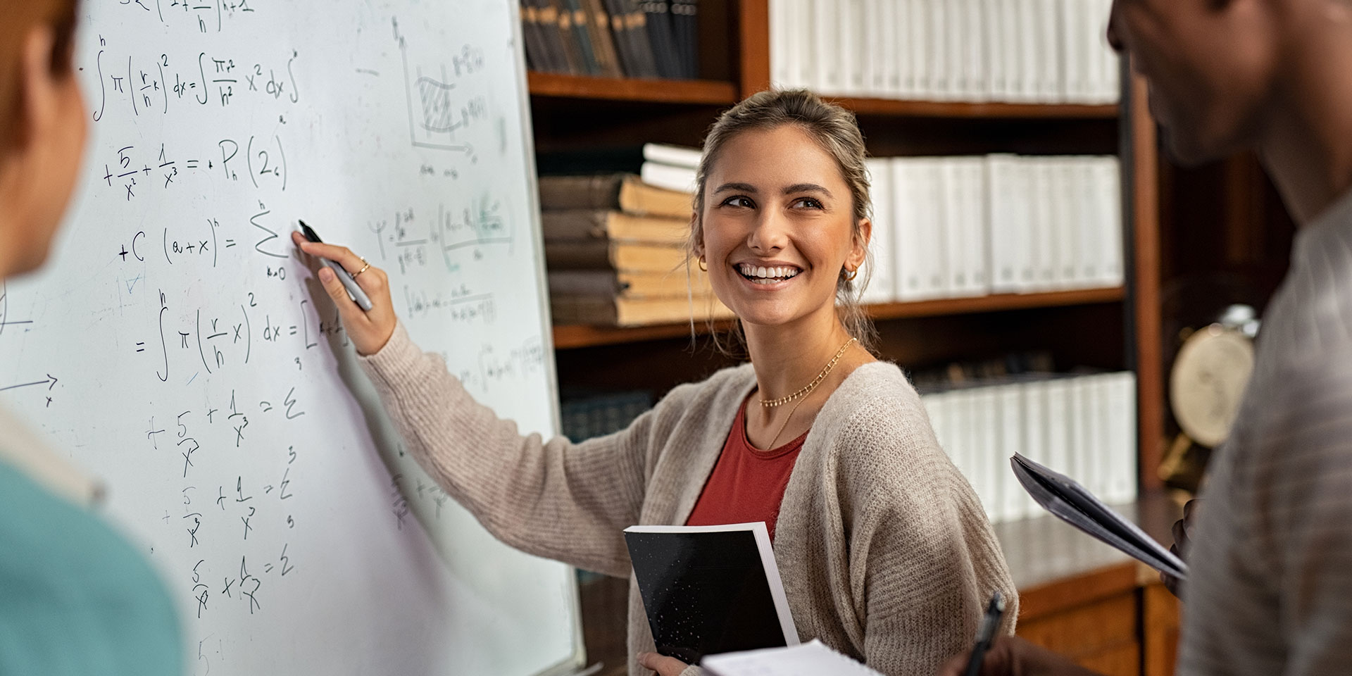 A teacher points out an equation on a whiteboard
