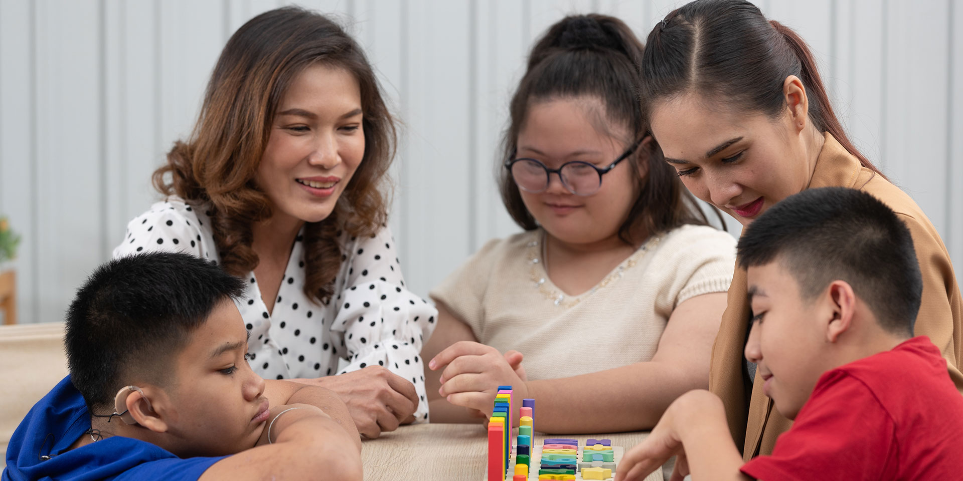 Two teachers work with three students with special needs