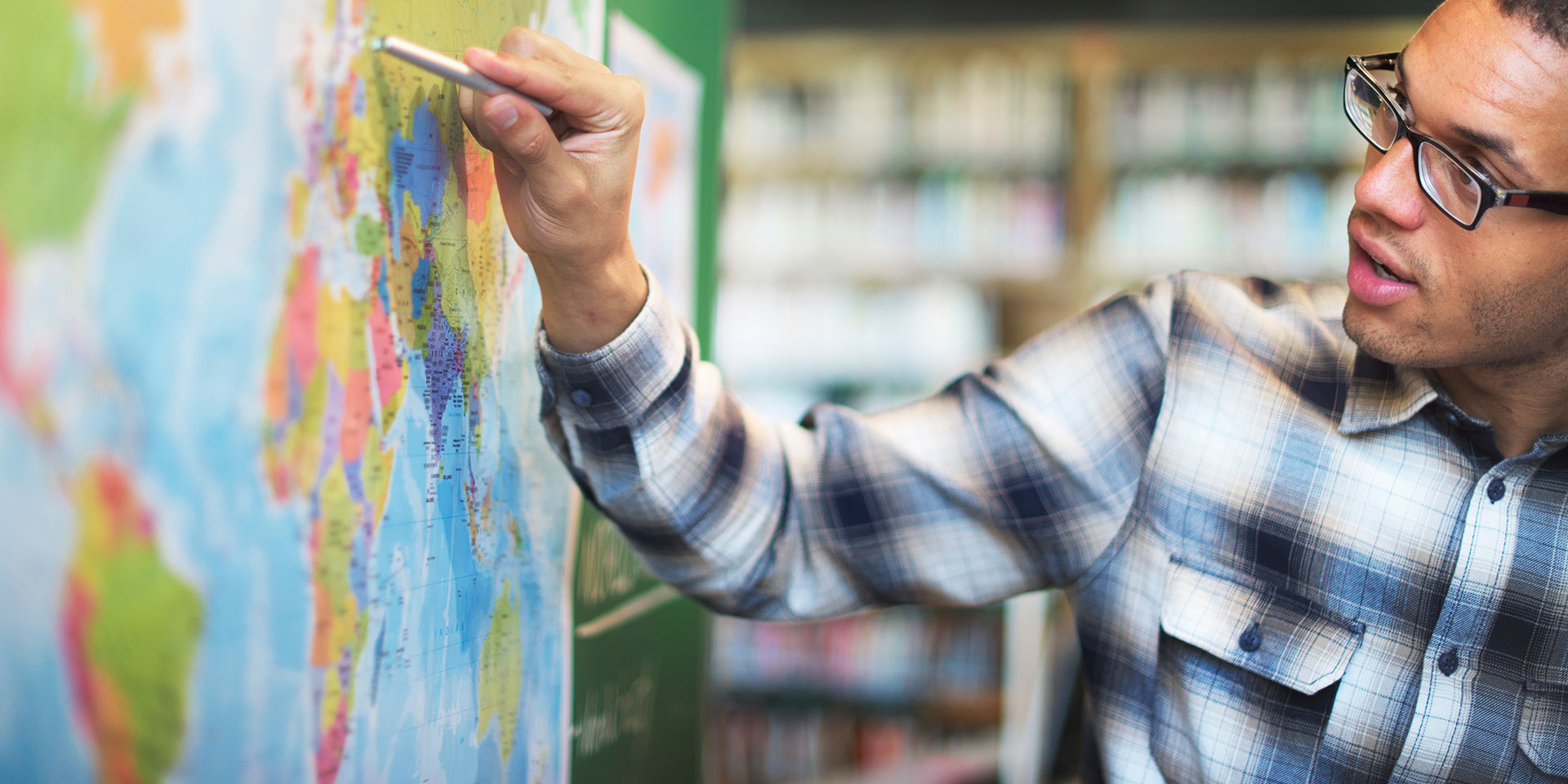 A teacher points out something on a world map