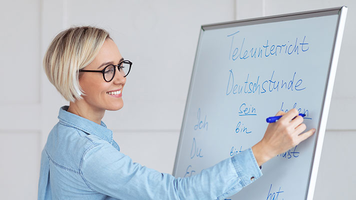 A teacher writes a German lesson on the white board