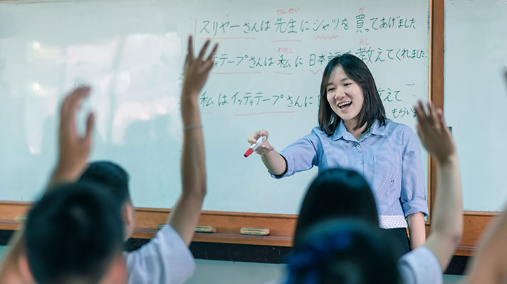 A teacher calls on students with a Japanese lesson on the whiteboard