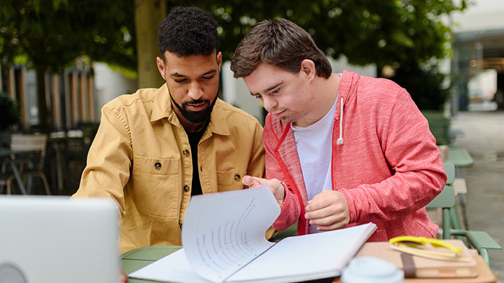 A male teacher works with a special education student on a project