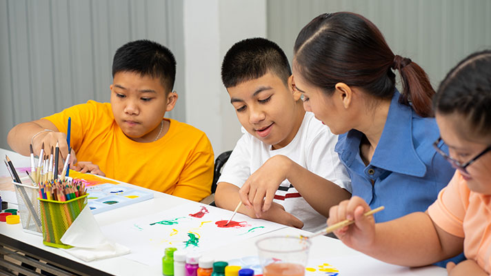 A teacher works with special education students on an art project
