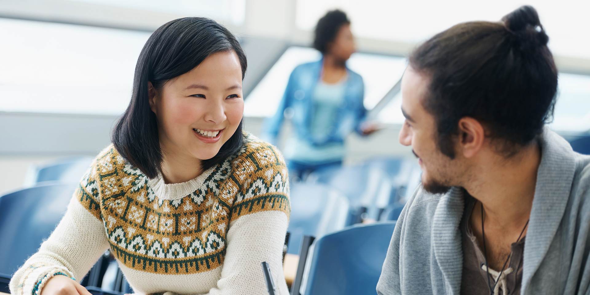 An Asian student looks at another student while going through some books.