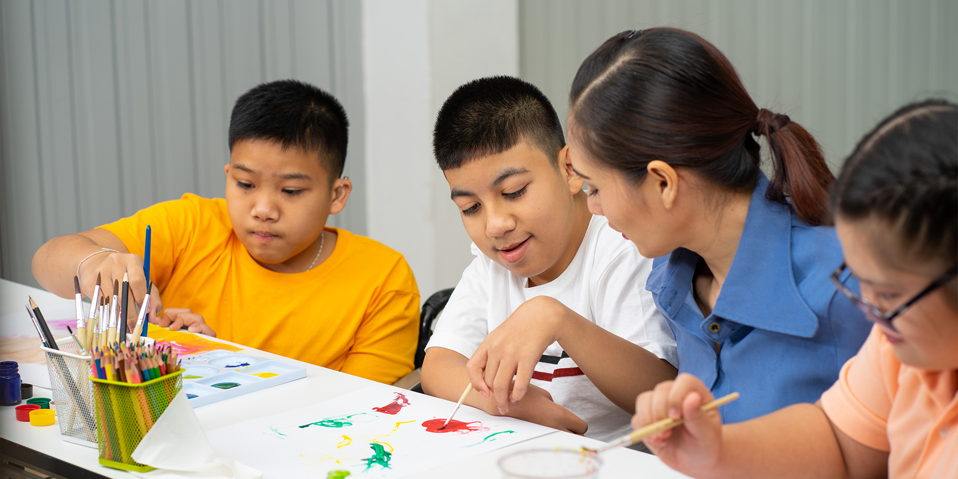 A teacher works with special education students on an art project