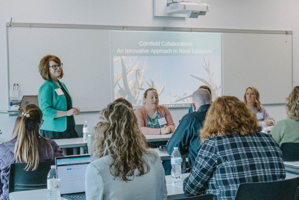 Rural Ed Summit attendees watching a presentation projected onto a whiteboard.