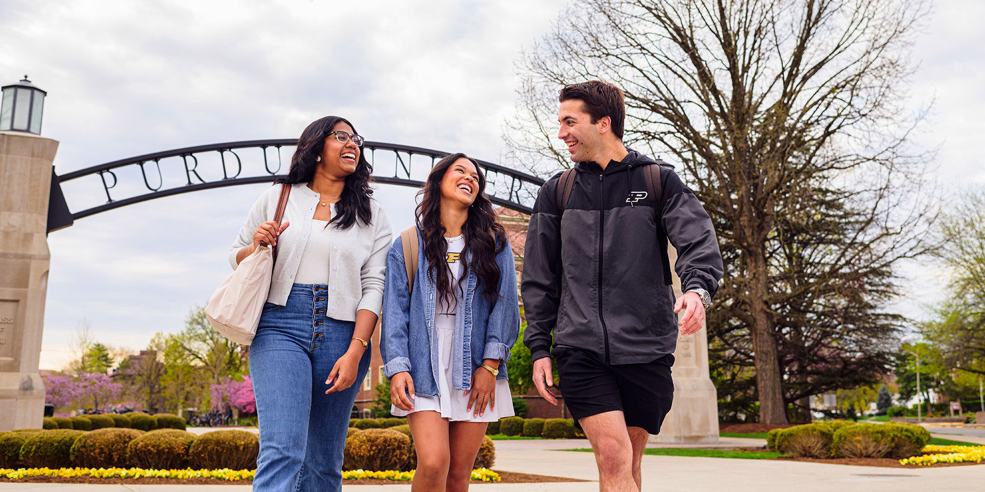 Three students walk under an arch on Purdue University's campus