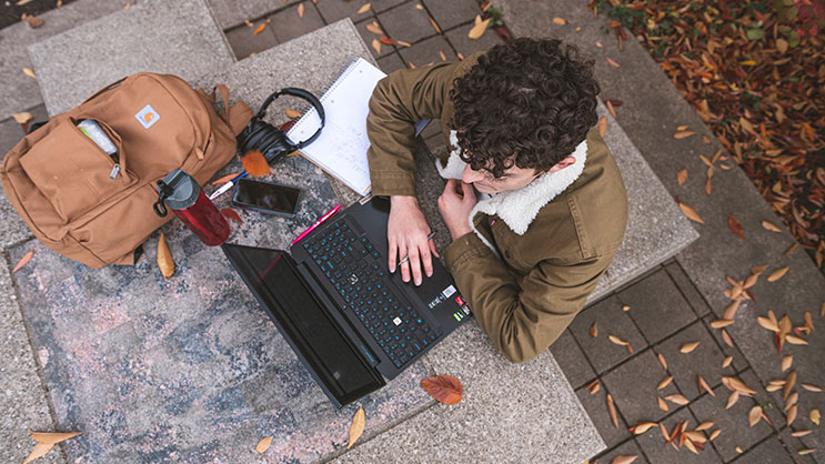 An overhead shot of a student working on a laptop outside at Purdue University
