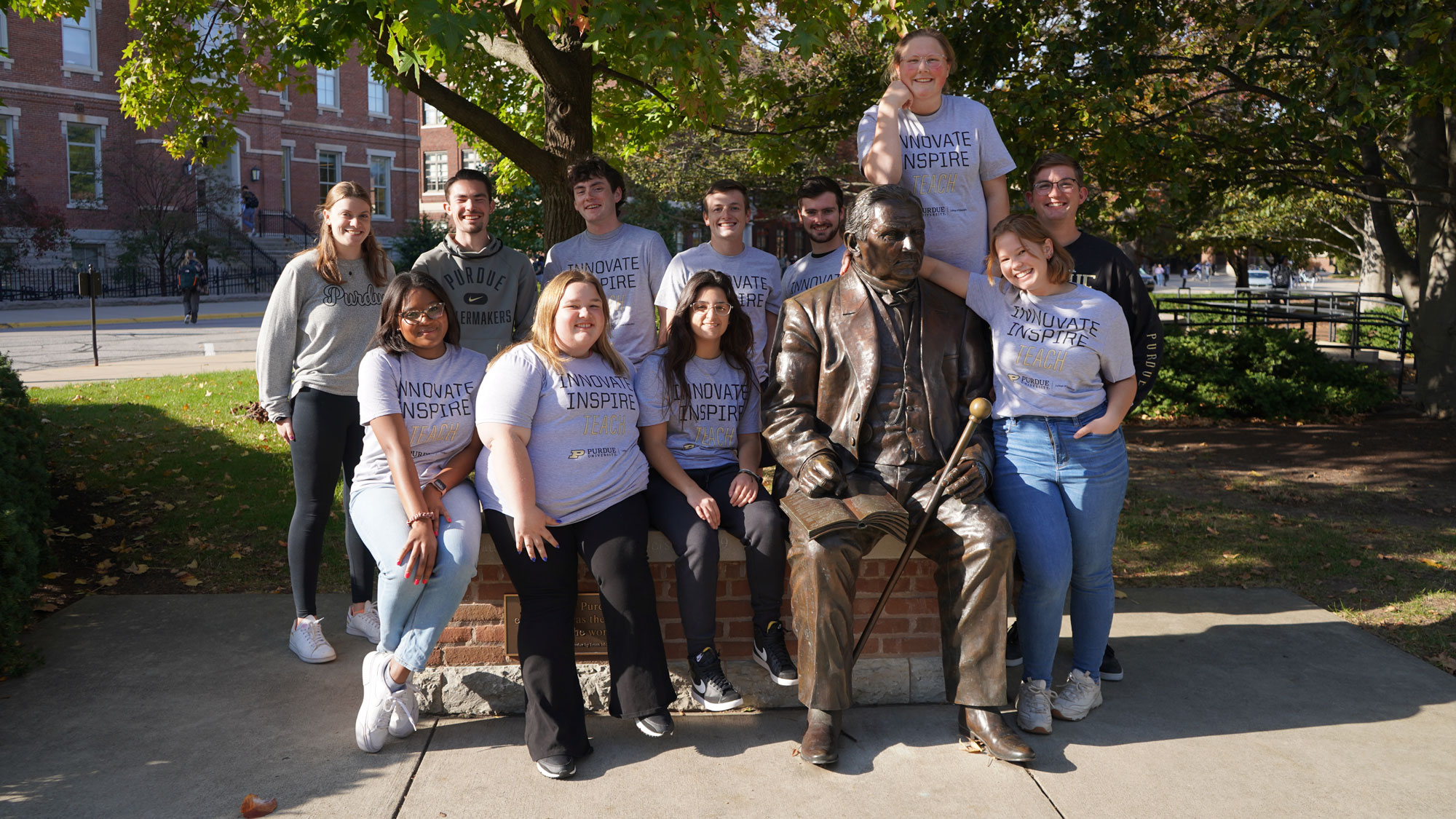 A group of College of Education students stand with the statue of John Purdue on Purdue's campus