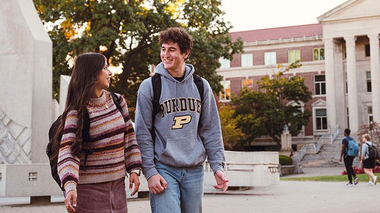 One male and one female student walk through Purdue University's campus