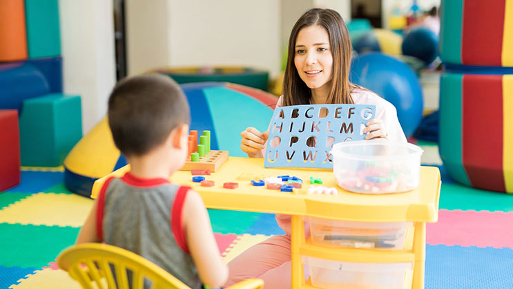 A teacher works with a student in a colorful classroom.