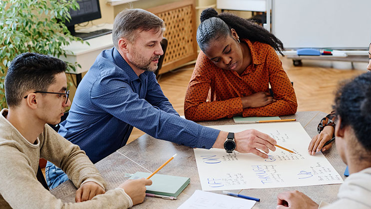 A teacher works with a group of students on a project. 