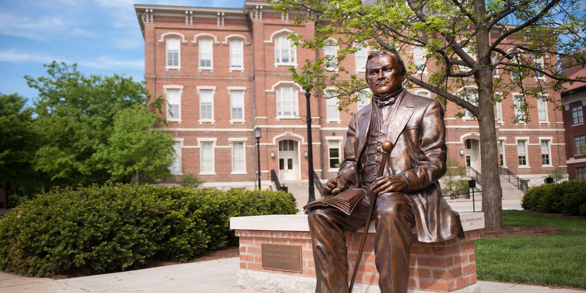 A statue of John Purdue seated on a bench outdoors.