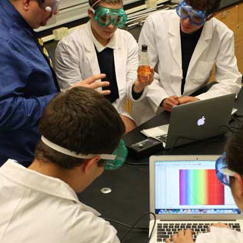 Students in white lab coats work on an experiment with CATALYST