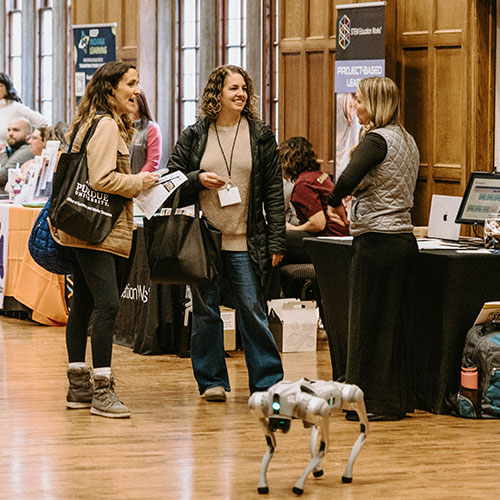 Two educators talk with a vendor at the Indiana STEM Education conference. A robotic dog is shown in the foreground.