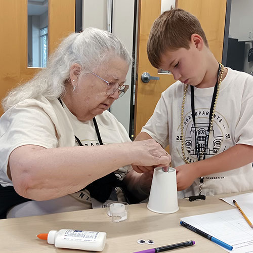 An older woman and a younger boy work on a project at CATALYST's Grandparents University program