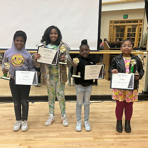 The four winners of a contest put on by CLEAR stand with their prizes