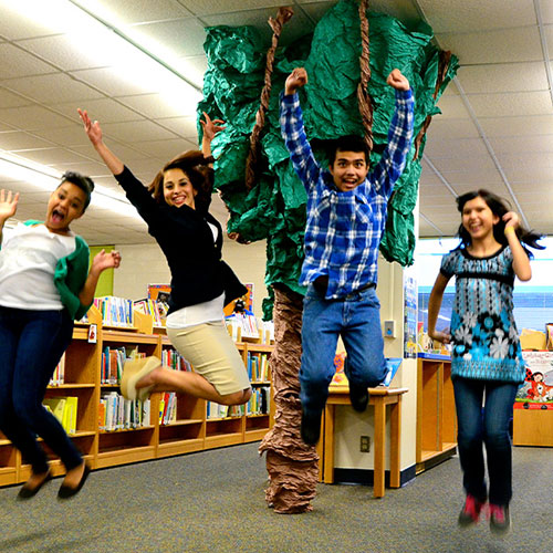 A group of students jump in the air in a school library