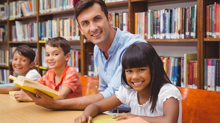 A male teacher reads with a group of students