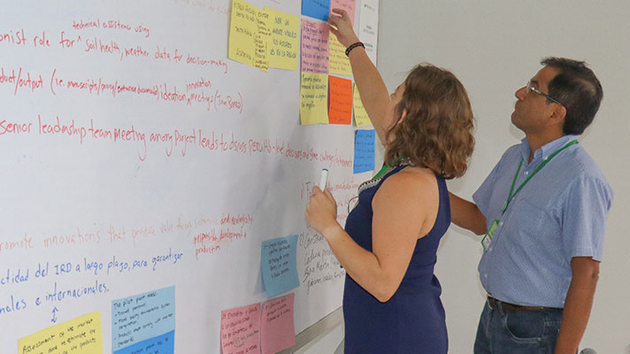 Two researchers work on a project on a whiteboard