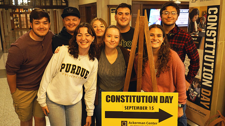 A group of Purdue University students stand next to a sign for Constitution Day