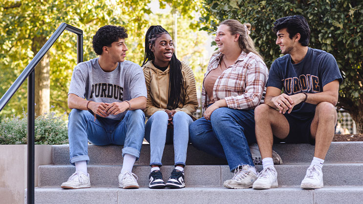 A group of four Purdue students seated on stairs outside.