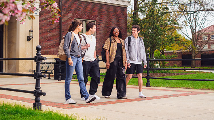 A group of four Purdue students walking out of an academic building.