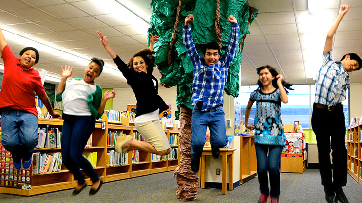A group of students jump in the air in a school library
