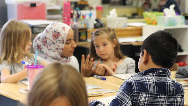 A student teacher helps children in a local classroom