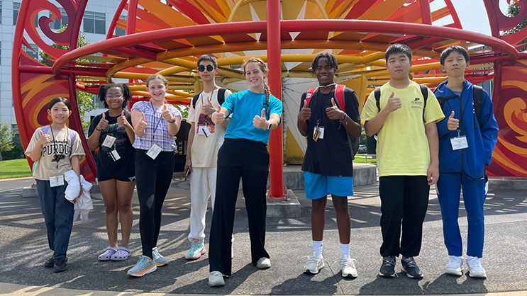 A group of students at the GER2I summer residential program stand in front of a sculpture at Purdue University