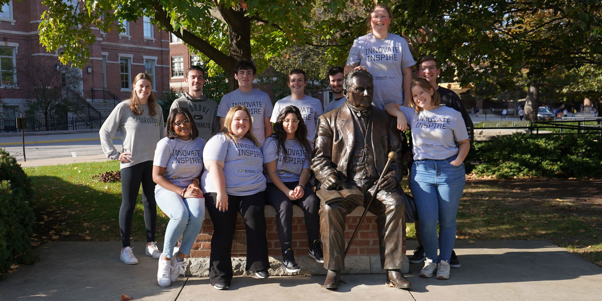 A group of Purdue University College of Education students pose with the statue of John Purdue on campus.