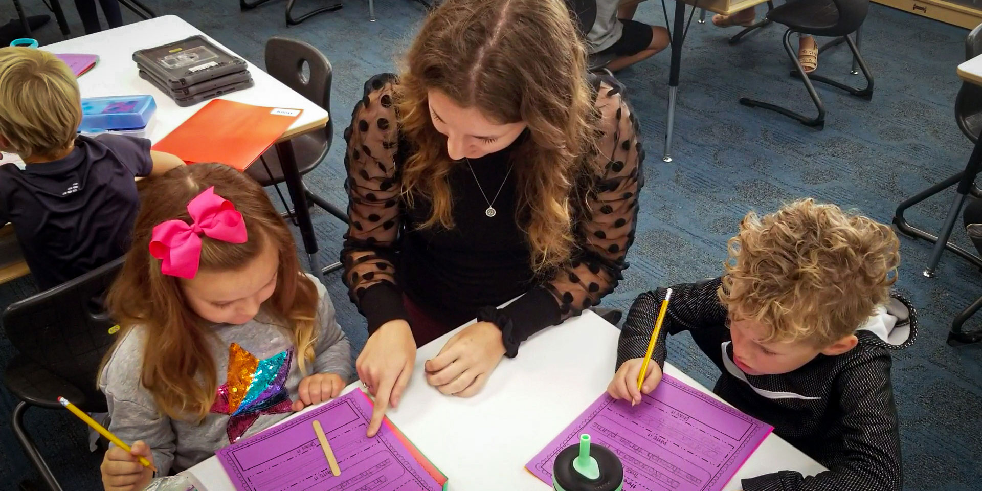 An undergraduate education student helping two elementary students with their homework.