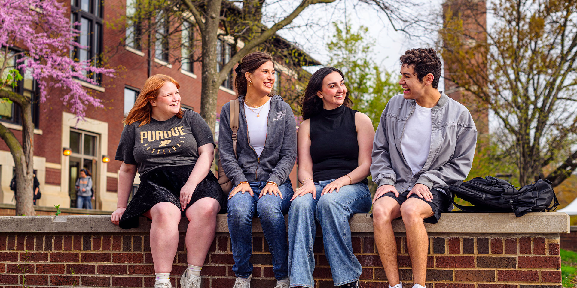 A group of four Purdue students seated on a bench outside.